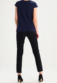 Top de manga corta azul marino combinado con pantalones negros ajustados. El conjunto presenta un diseño sencillo, una textura suave y zapatos de tacón alto negros.
