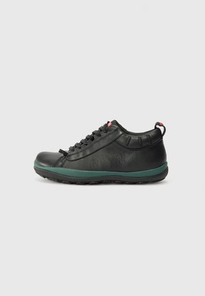 Baskets en cuir noir avec semelle en caoutchouc vert, bout arrondi, design à lacets et une languette à l'arrière. Tige texturée avec des coutures discrètes.