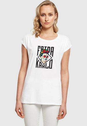 Hvid bomulds t-shirt med et grafik af Frida Kahlo iført en blomsterkrone, med fed sort tekst og en diamantform, der indrammer billedet.