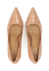 Une paire de ballerines beiges nude à bout pointu avec texture crocodile et semelles rembourrées sur fond blanc.