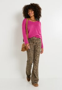 Suéter rosa de punto, pantalones acampanados marrones con estampado de leopardo, bolso cruzado marrón y zapatos marrones. Materiales de mezcla de poliéster y algodón.