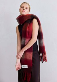 Écharpe dégradée rouge et grise en laine douce, munie d'extrémités à franges et d'une étiquette blanche portant l'inscription "ARCTIC FOX".