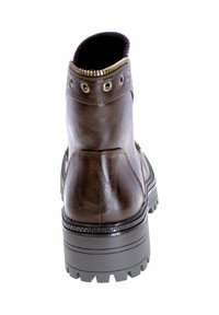 Stivaletto alla caviglia in pelle marrone con superficie texturizzata, punta arrotondata e suola spessa in gomma con motivo antiscivolo. Occhielli decorativi vicino alla parte superiore.