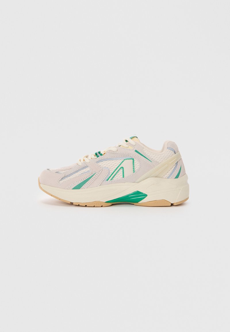 Sport sneaker in beige with green accents, mesh and synthetic upper, textured surface, rubber sole, and a chunky design.