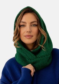 Zielony, dzianinowy szalik z kapturem o teksturowanym wzorze, dopasowany ściśle do szyi, w zestawie z niebieskim sweterem.