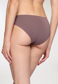 Slip in cotone borgogna con una texture liscia, design a vita alta e dettagli di cucitura sottili sulla cintura e sulle aperture delle gambe.