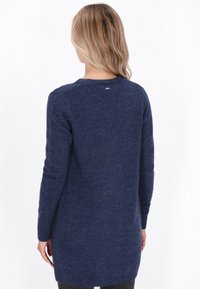 Granatowy sweter z długim rękawem o teksturowanym wykończeniu, okrągłym dekolcie i subtelnym logo z tyłu. Miękki, dziany materiał.