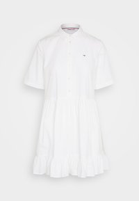 White cotton dress with short sleeves, a buttoned collar, and a flared ruffle hem. Features a small logo on the chest.