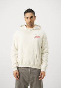 Sudadera crema con bordado rojo "Benfica" en el lado izquierdo del pecho, con un bolsillo frontal, capucha con cordones y puños ribeteados en las mangas y en el dobladillo.