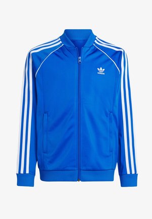 Veste de survêtement Adidas bleue à manches blanches à trois bandes, fermeture éclair frontale, poignets et ourlet côtelés, avec logo Adidas sur la poitrine.