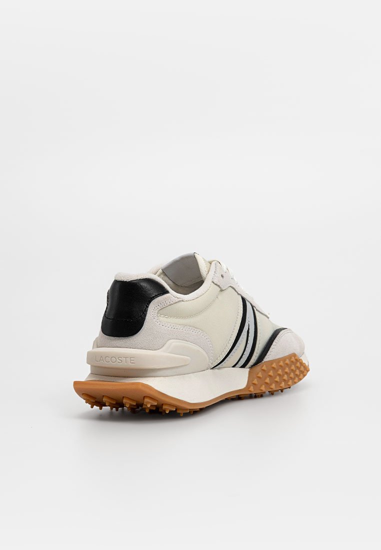 Zapatillas Lacoste en una combinación de colores blanca y negra, fabricadas con materiales de ante y textil, que cuentan con una suela de goma texturizada y franjas en contraste.