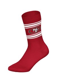Czerwone skarpetki wykonane z tkaniny o prążkowanym wzorze. Posiadają białe paski i logo na górnej części. Gładka tekstura na całej powierzchni.