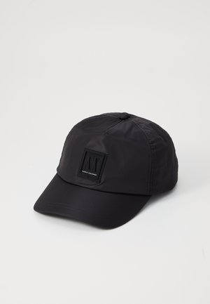 Gorra de béisbol negra hecha de tela ligera. Cuenta con una visera plana y un parche de logo cuadrado en la parte frontal. Se pueden ver las costuras.