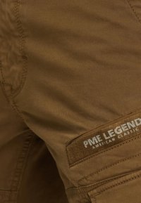Smešane smeđe lagane cargo kratke hlače s glatkom teksturom, koje sadrže PME Legend oznaku i više džepova za pohranu.