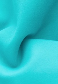 Türkiissinine kangas, millel on sile tekstuur, kerge läike ja pehme langevus, millel on kogu ulatuses keerukad kootud mustrid.