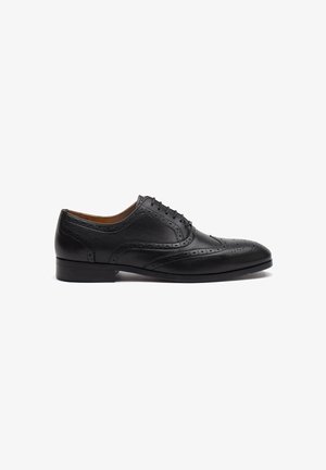 Chaussure habillée en cuir noir avec un bout arrondi, des perforations décoratives et un système de laçage. Elle présente un talon bas.