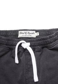 Tummanharmaat elastiset vyötäröshortsit valkoisella kiristysnauhalla, joissa on "Band of Rascals" -etiketti ja pehmeä kangaspinta.