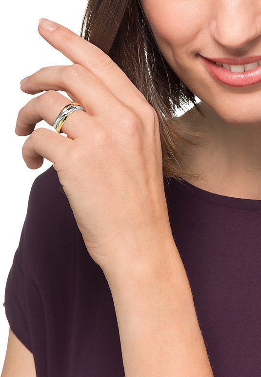 Three intertwined rings in silver, gold, and rose gold metals, featuring a smooth finish. Worn on the ring finger, partially visible hand.