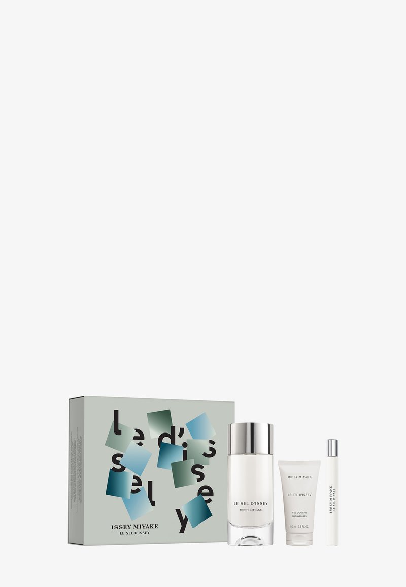 Issey Miyake Le Sel D'Issey Geschenkset bestehend aus einer klaren Flasche, weißem Duschgel und einem kleineren Spray, verpackt in einer grün-blau gemusterten Box.