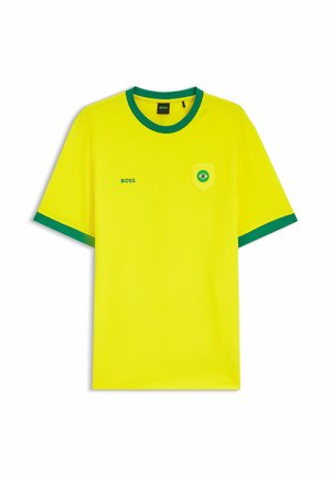 Gelbes kurzärmeliges Hemd mit grünem Kragen und Ärmelenden, "BOSS" Schriftzug auf der linken Brust und einem brasilianischen Flaggenemblem auf der rechten Brusttasche.