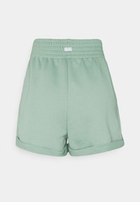 Světle zelené bavlněné šortky se smockovaným elastickým pasem, ohrnutými okraji a malou logovou etiketou umístěnou v pase. Měkká textilie.