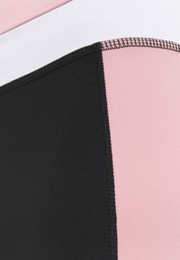 Tessuto a blocchi di colore con pannelli neri, rosa e bianchi, con cuciture piatte. La texture è liscia ed elastica, adatta per abbigliamento sportivo.