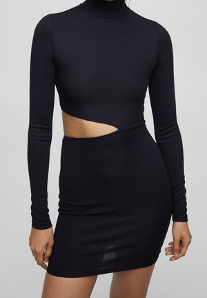 Black ribbed dress with long sleeves, high neckline, and a diagonal midriff cutout showing bare skin on the left side.