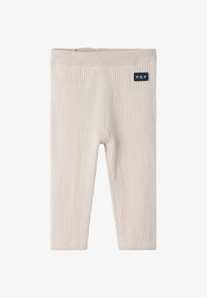 Leggings côtelés beige clair avec une texture douce, dotés d'une ceinture élastique et d'un petit patch logo bleu marine sur le coin supérieur gauche.