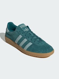 Türkiisssuede sneaker kolme heledat sinise triibuga, lamela varbaosas ja tekstuurse kummist välispinnaga. Omab pehmet keelt ja voodrit.