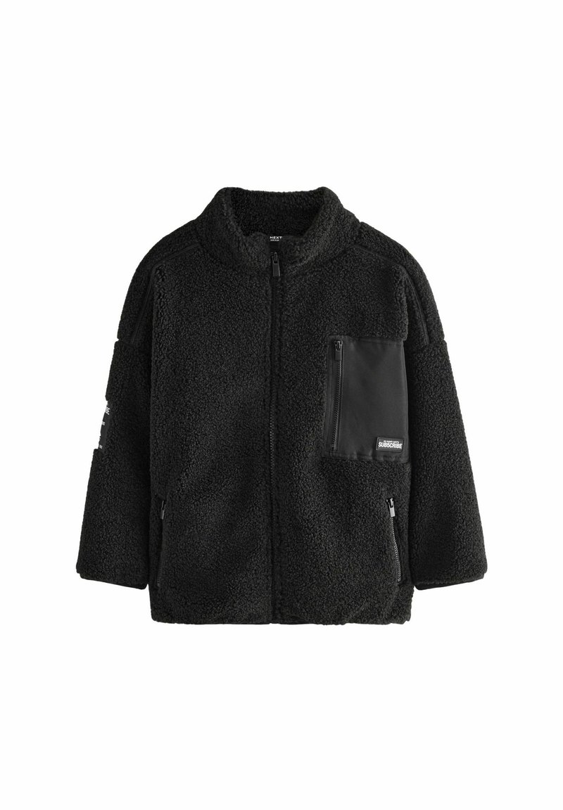 Veste en polaire noire avec une surface texturée, col haut, fermeture éclair à l'avant et une poche poitrine avec un détail en tissu noir.