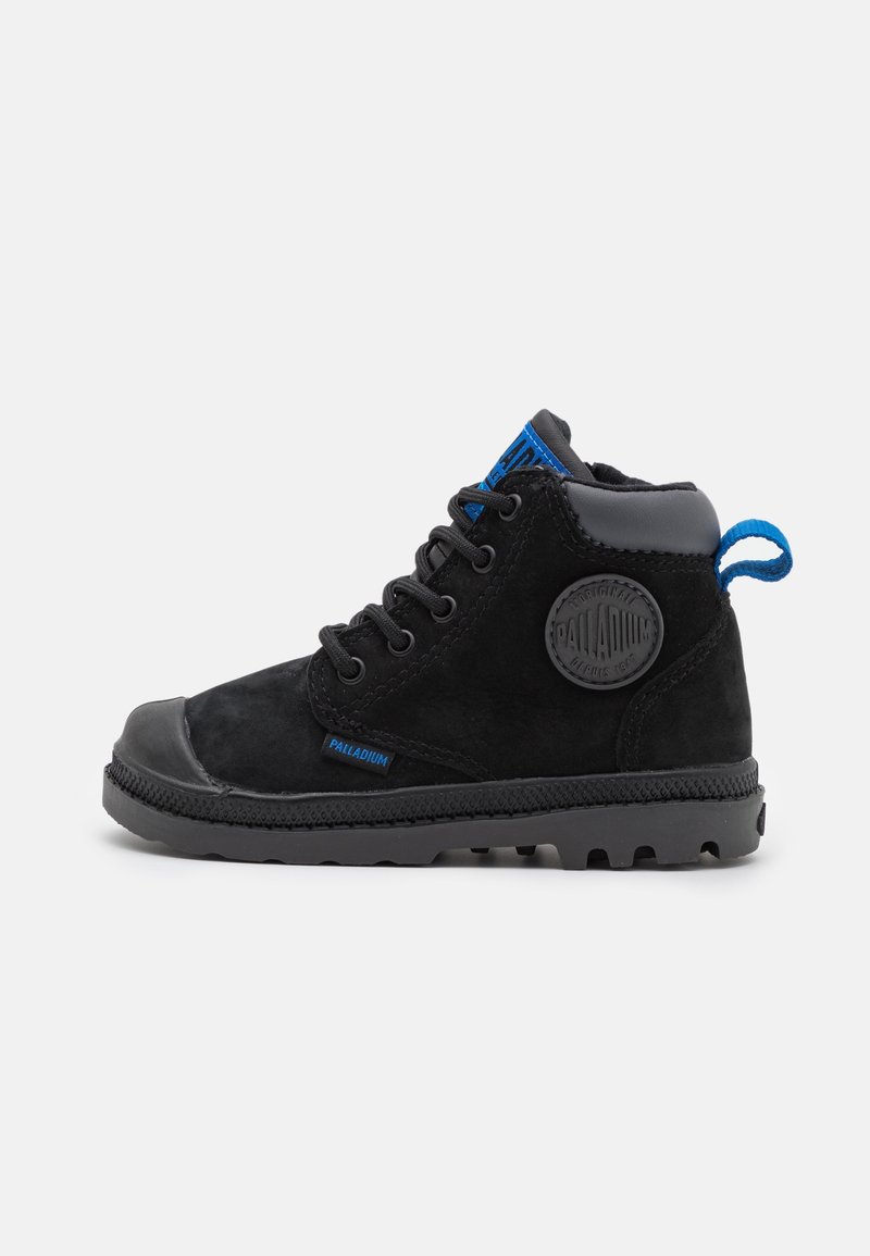 Botte montante noire Palladium avec semelle en caoutchouc, languette en tissu bleu, patch logo rond, et fermeture avant à lacets.