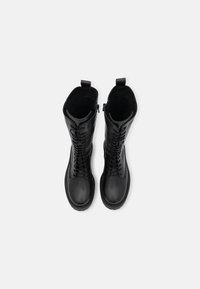 Bottes noires imperméables avec une finition en cuir lisse, lacets à l'avant et fermeture éclair sur le côté. Elles disposent d'une semelle robuste et d'une doublure intérieure moelleuse.