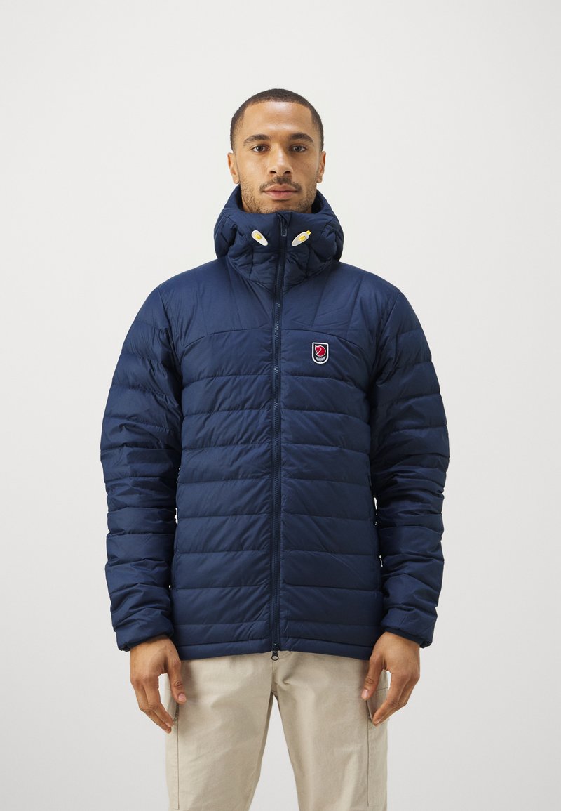 Námornícky puffový kabát s horizontálnym prešívaním, vysokým golierom a zipsom. Obsahuje nášivku s logom na ľavej hrudi a žlté akcentované gomb�íky.
