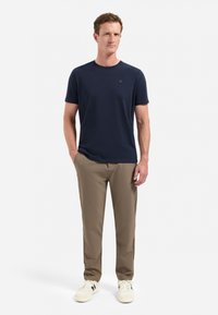 Marineblauwe t-shirt met korte mouwen, van katoen, ronde hals, gecombineerd met kaki broek, taps toelopende pasvorm, witte sneakers, eenvoudige uitstraling zonder patronen.