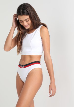 Fehér sportmellény lekerekített nyakkivágással és fehér bikini alsó, amely piros és sötétkék elasztikus derékpánttal rendelkezik, rajta a FILA logóval.