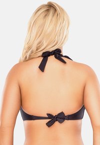 Top bikini nero con design a halter, caratterizzato da spalline annodate e dettaglio a fiocco sul retro. Texture liscia e copertura minima.