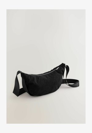 Banane en velours côtelé noir avec fermeture éclair lisse, sangle en tissu ajustable et surface douce et texturée. Design simple et incurvé.