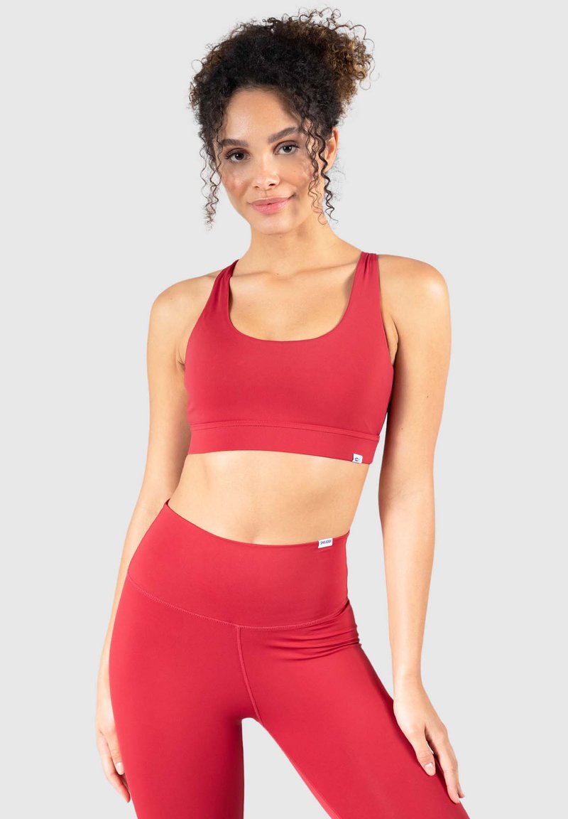 Sujetador deportivo rojo y leggings de cintura alta en una tela suave y elástica. Diseño sencillo sin patrones y con pequeños acentos de logo.