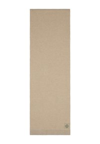 Bufanda de punto beige confeccionada en una tela suave. Presenta un pequeño parche con el logo y un borde texturizado ligeramente más grueso. Forma rectangular y larga.