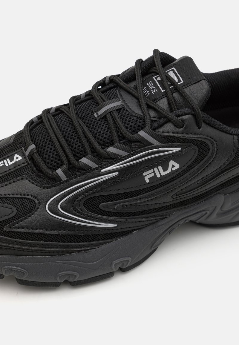 Zwarte sportieve schoen met een bovenwerk van mesh, een slank ontwerp, grijze accenten en een getextureerde zool voor grip. Bevat veters en logo-branding.