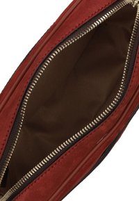 Clutch in suede rosso con apertura a zip dorata, che mette in mostra un interno in tessuto marrone. Texture liscia con cuciture dettagliate lungo i bordi.