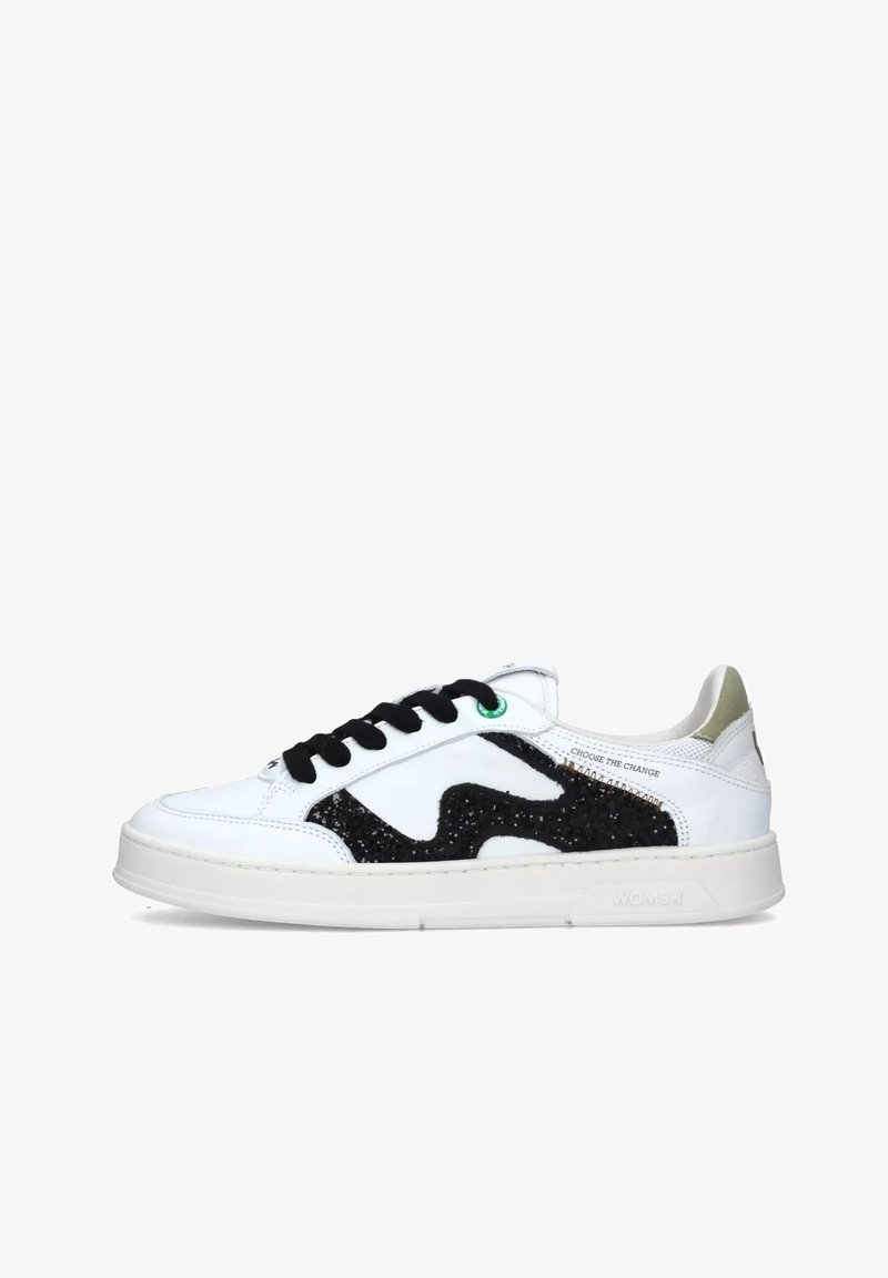 Sneakers bianchi con un design testurizzato nero, lacci neri e un accento verde. Presentano una suola in gomma cremosa e un dettaglio dorato metallico sul tallone.