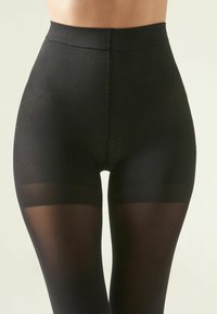 Sorte højtaljede tights med et tekstureret, perforeret design på kroppen, der overgår til gennemsigtigt stof på benene.