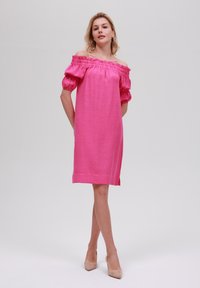 Rosa avskuren klänning med puffärmar, texturerad tyg, knälång, med sidoklipp, kombinerad med nude klackar.