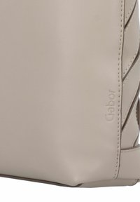 Beige Lederhandtasche mit glatter Textur, die ein geflochtenes Design aufweist und das Gabor-Logo an der Seite geprägt hat.
