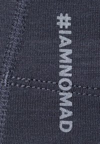 Donkerblauwe stof met een gladde textuur, voorzien van witte bedrukking van "#IAMNOMAD" en zichtbare stiksels. Close-up weergave.