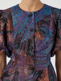 Abito colorato e con fantasia, caratterizzato da un mix di trame viola, blu e rame. Maniche a sbuffo corte e dettagli con bottoni neri.