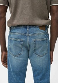 Jasnoniebieskie jeansy z denimu o luźnym kroju, z dwoma tylnymi kieszeniami i minimalnym przetarciem. Pas spodni ozdobiony jest brązową skórzaną metką.