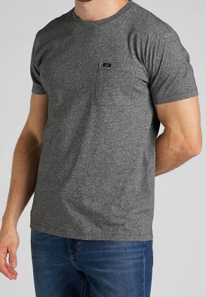 T-shirt gris à manches courtes en tissu texturé. Comprend une poche poitrine et une petite étiquette de marque. Coupe décontractée avec un col rond.