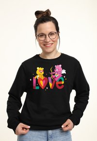 Felpa nera con orsetti cartoon colorati e la parola "Love" in vivaci lettere arcobaleno. Il design include cuori e accenti giocosi.
